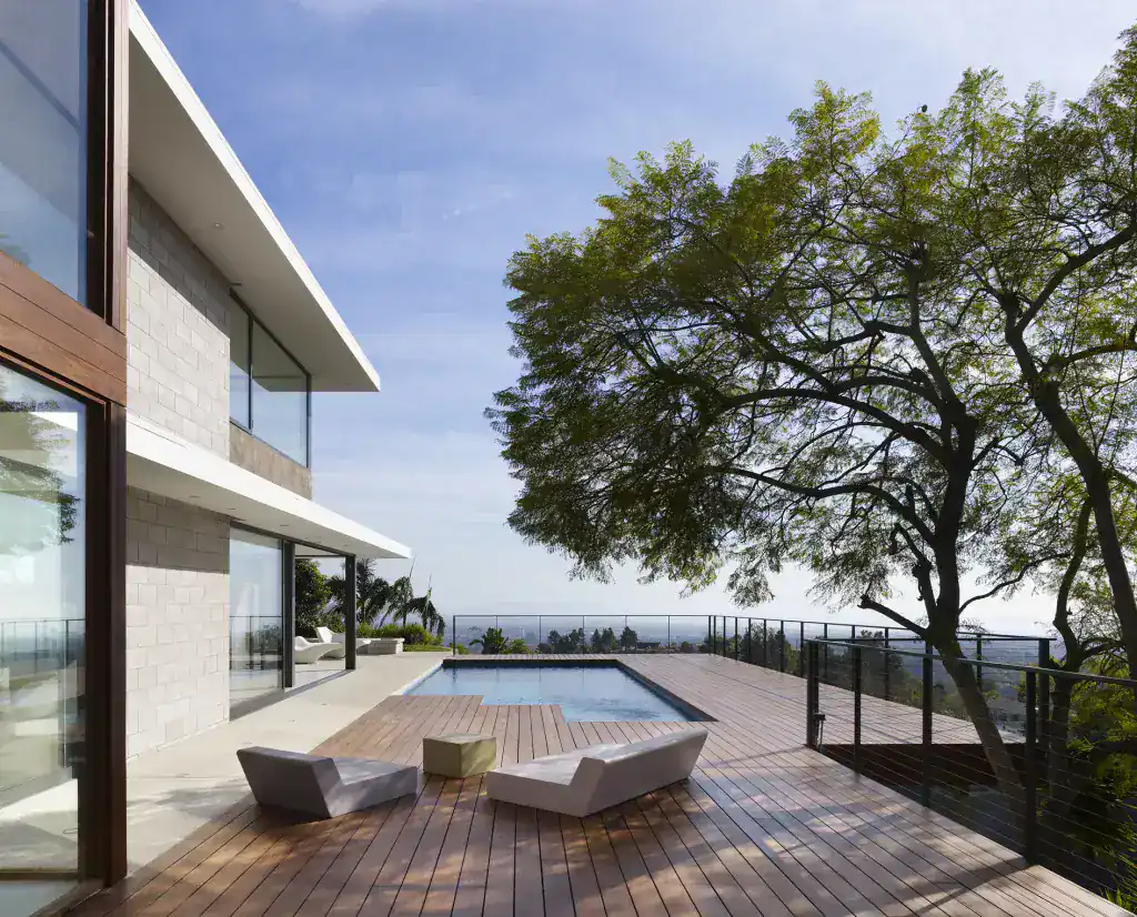 Modern house exterior with a pool and wooden deck, featuring clean lines, large glass windows, and minimalist furniture.