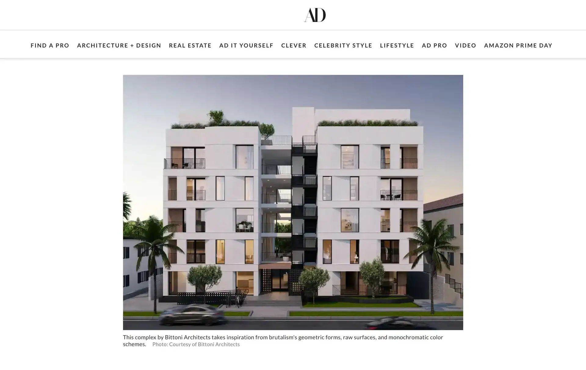 Contemporary white apartment building with geometric forms and recessed balconies, featuring large windows and rooftop greenery.