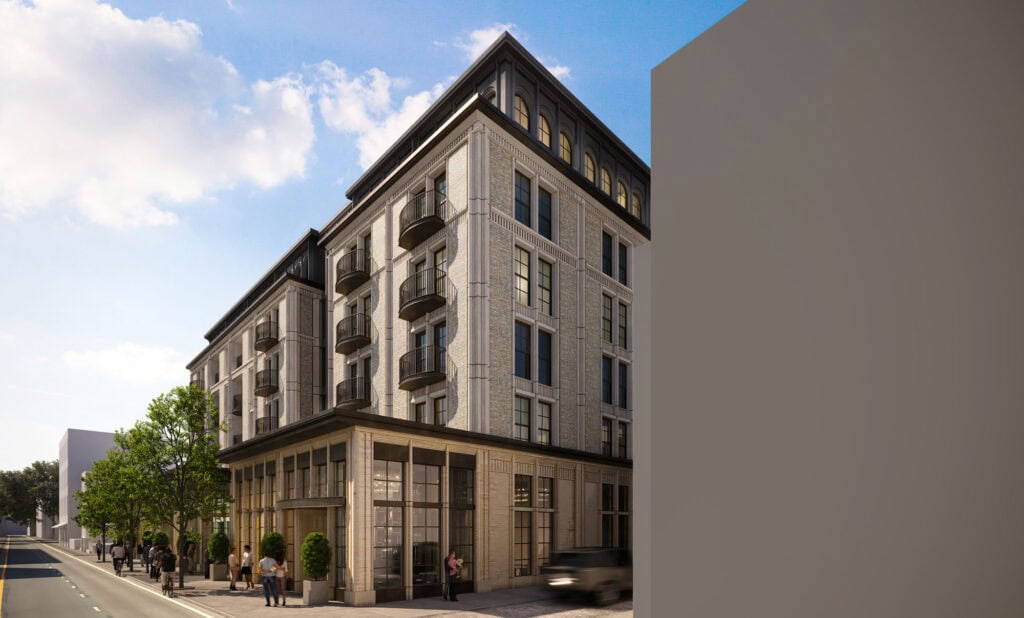 Elegant six-story building with classical architectural style, brick and stone façade, rounded balconies, large glass storefronts, and decorative cornices.