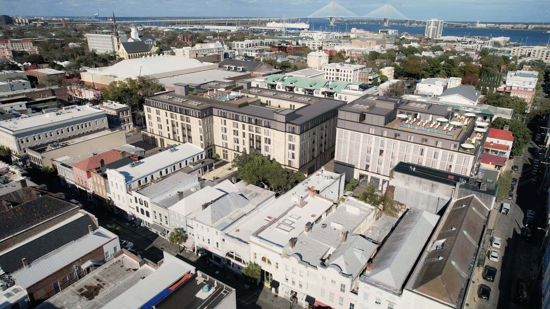 Modern mixed-use building with rooftop terraces, featuring a blend of classic and contemporary architecture, located in an urban setting with a bridge in the background.