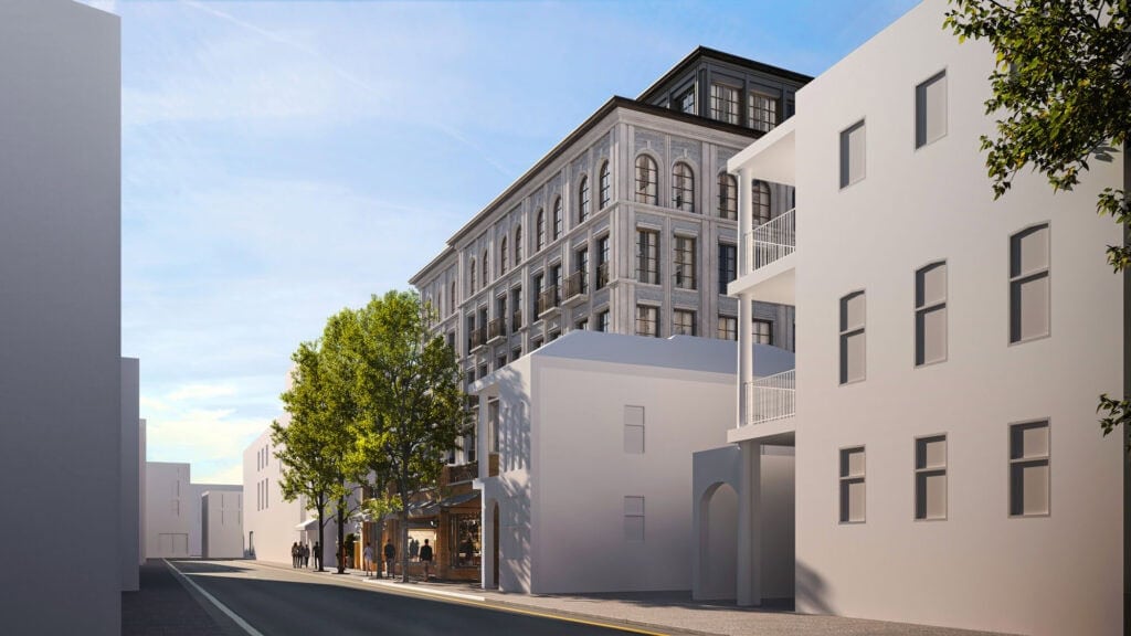 Elegant stone façade with classical arched windows and decorative moldings, topped with a modern black rooftop extension.