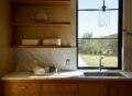Sunlit laundry room with oak cabinetry, marble countertops, and a large window overlooking a landscaped yard